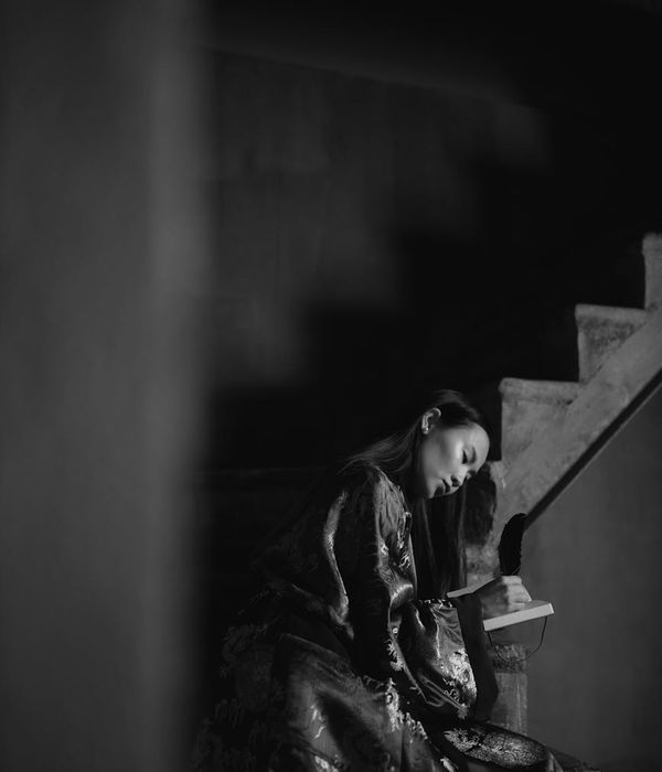 Woman in a calm balancing pose against a dark background.